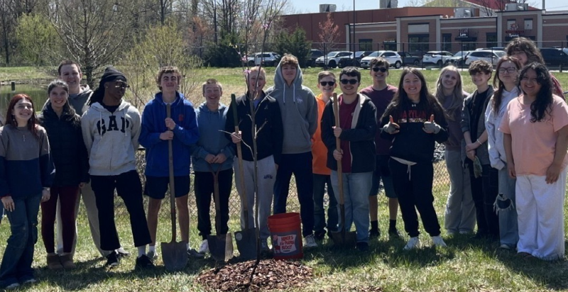 Group of high school students stand outside with their sapling