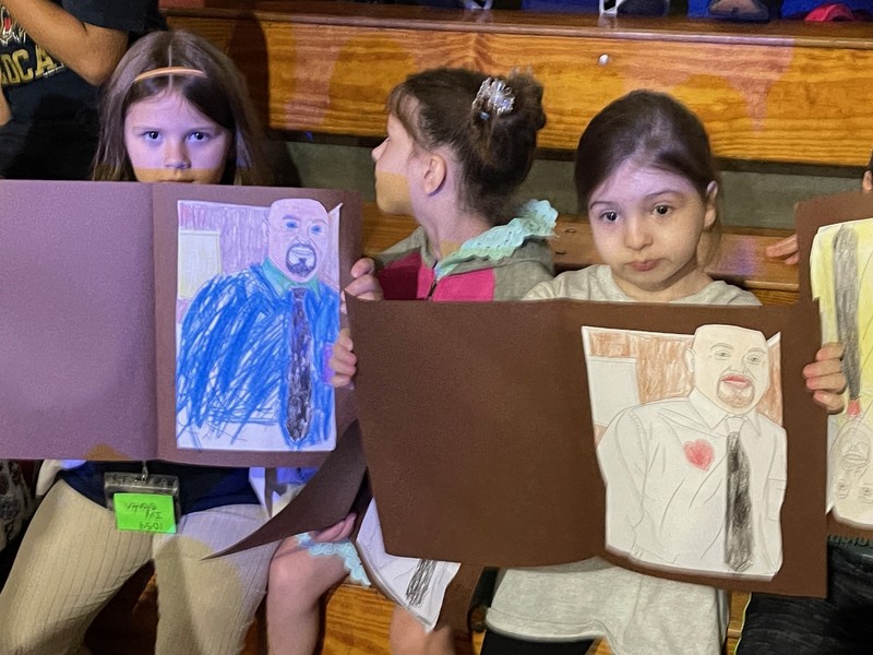 Students display their coloring sheets for Mr. Boggs.