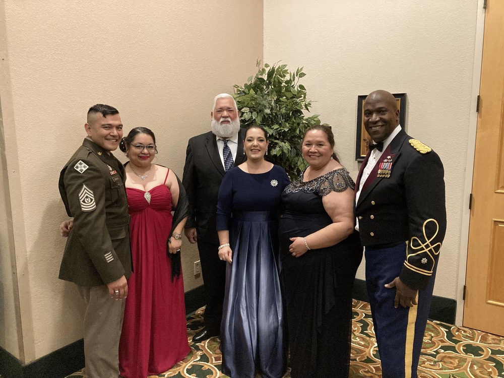 people in dresses and suits posing for a picture