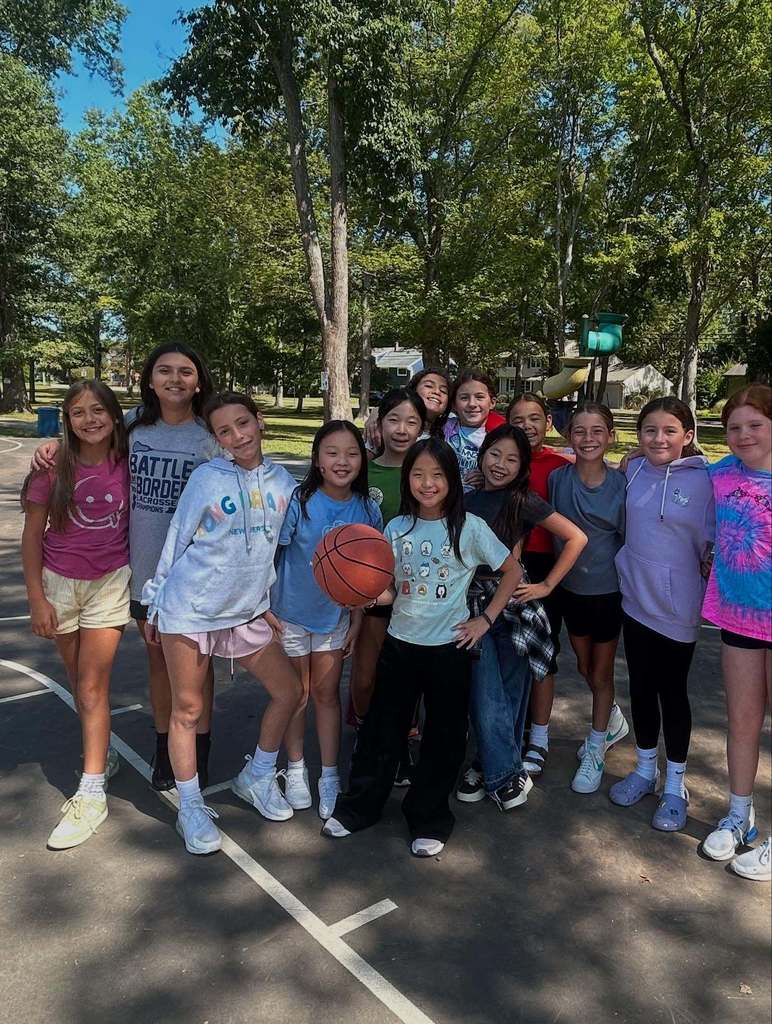 Students standing on a basketball court smiling