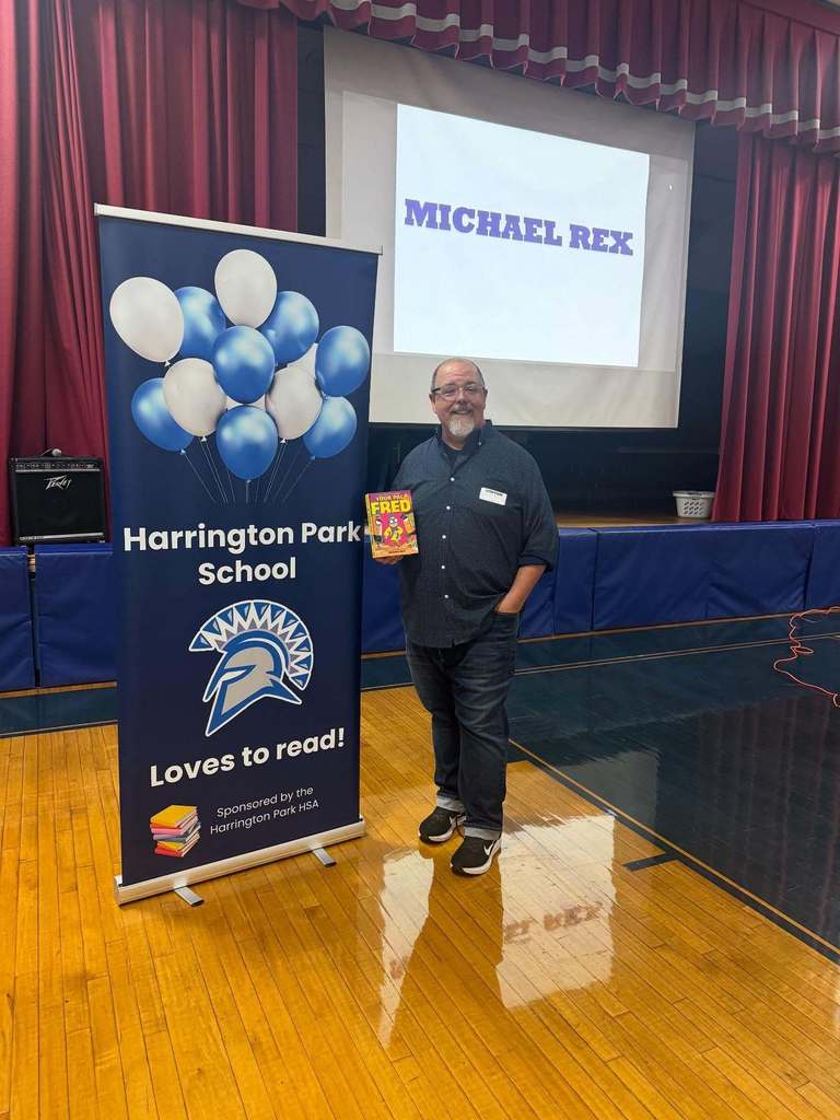 Author Michael Rex Stands with a Harrington Park loves to read banner during an Author Visit at the HP School.