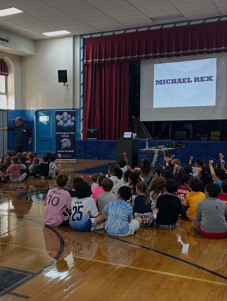 Author Michael Rex engages with students who are raising their hands during an Author Visit at the HP School.