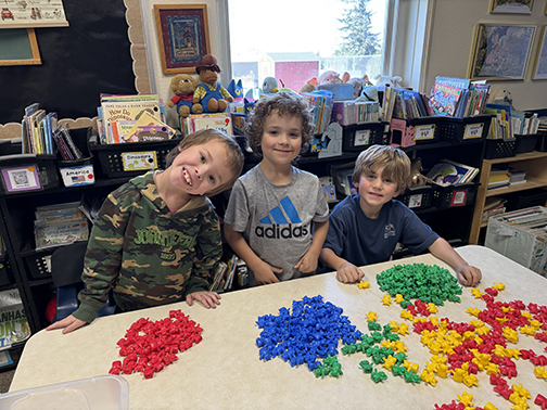 3 smiling kids with blocks