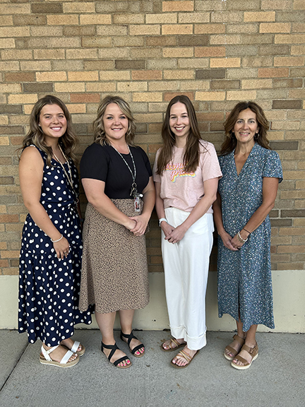 4 female teachers posing outside a building