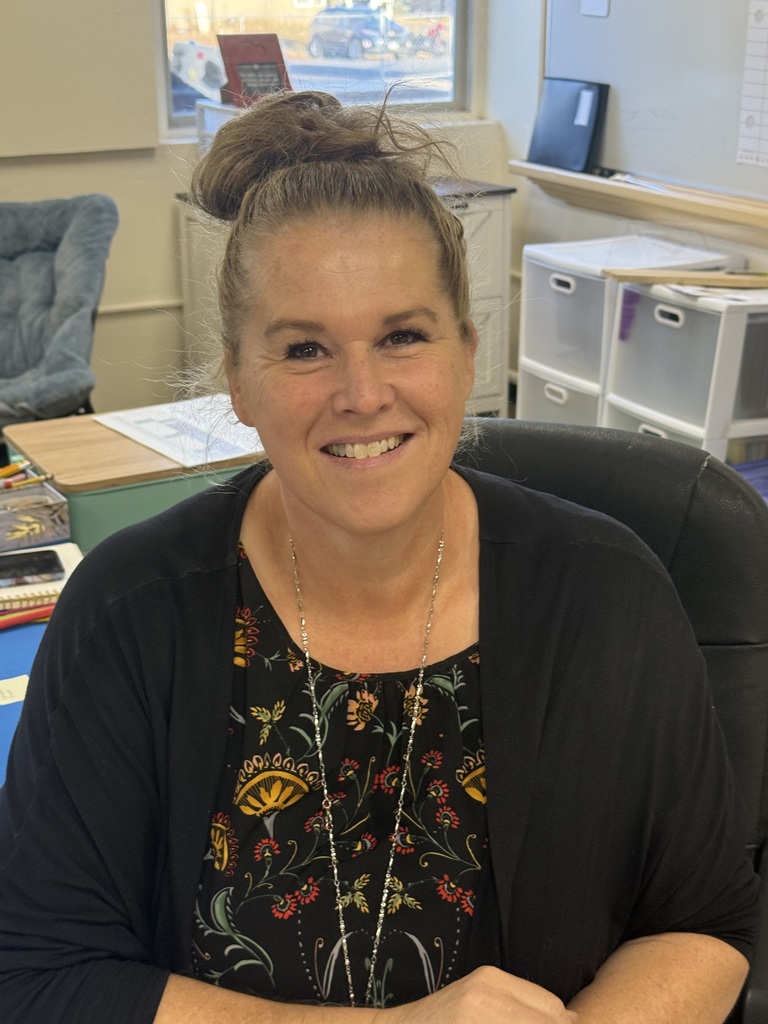 teacher sitting in desk posing for the camera