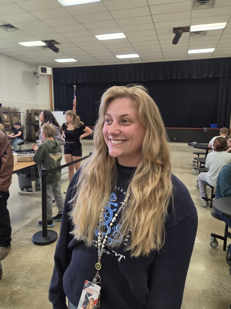 a woman photographed looking away from the camera and smiling with children in the background.