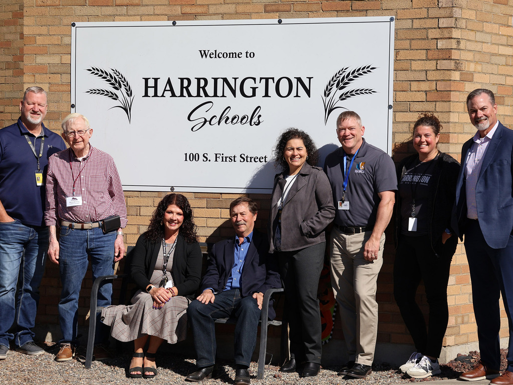 Several people posed in front of the Harrington Schools sign