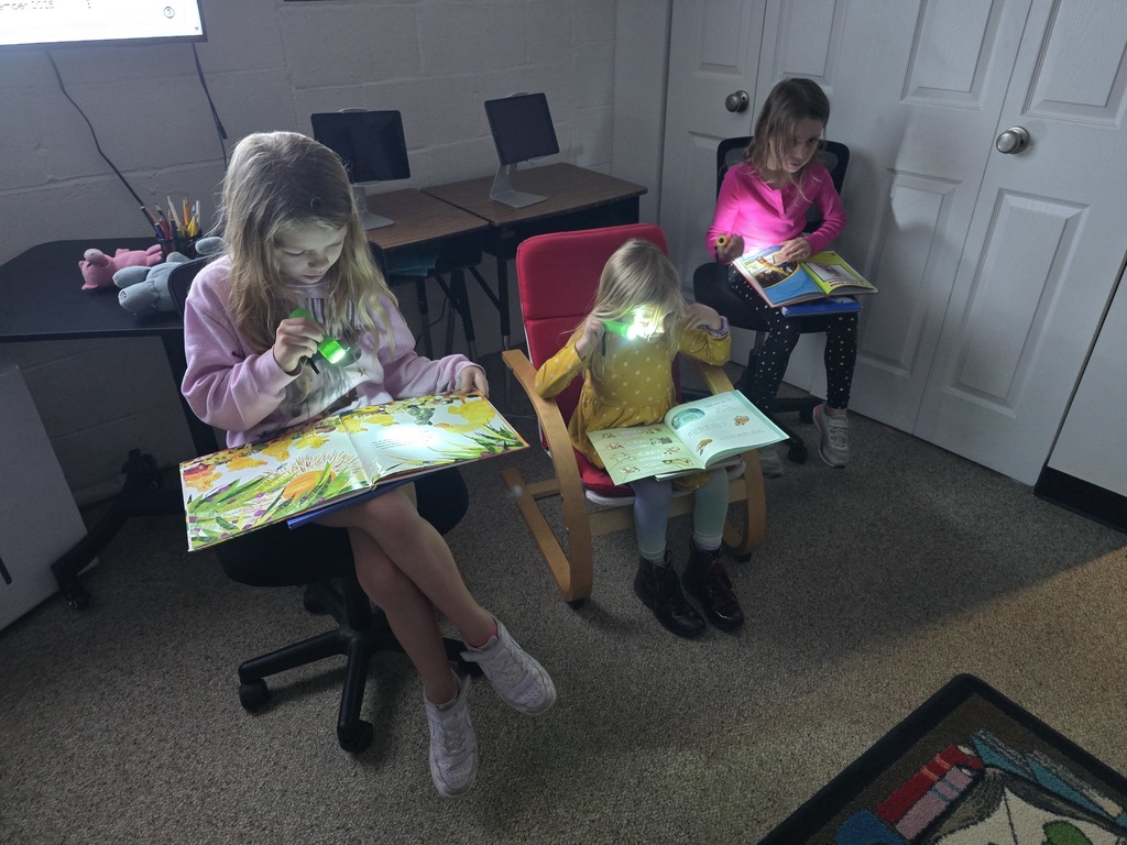 First grade students reading with flashlights in the library