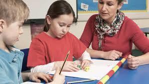 Teacher helps two students use dice and blocks for a math task.