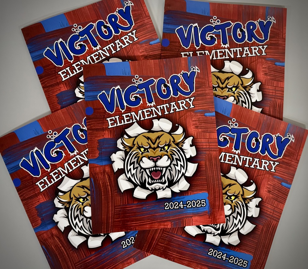 Five school folders with "Victory Elementary 2024-2025" on the cover and a fierce tiger mascot breaking through the background