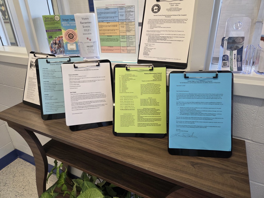 A wooden table in a school welcome area holds clipboards with Title I information sheets, flyers, and brochures for parents and families.