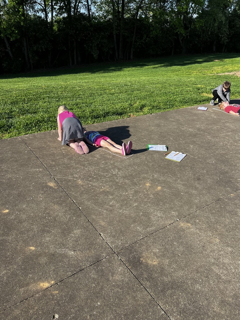 students using chalk to trace the shape of their bodies to measure.