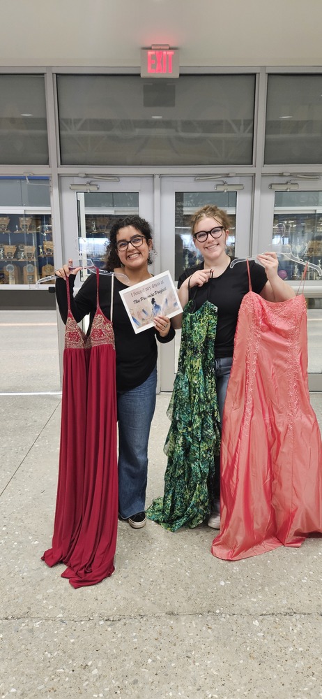 students holding up prom dresses to showcase them