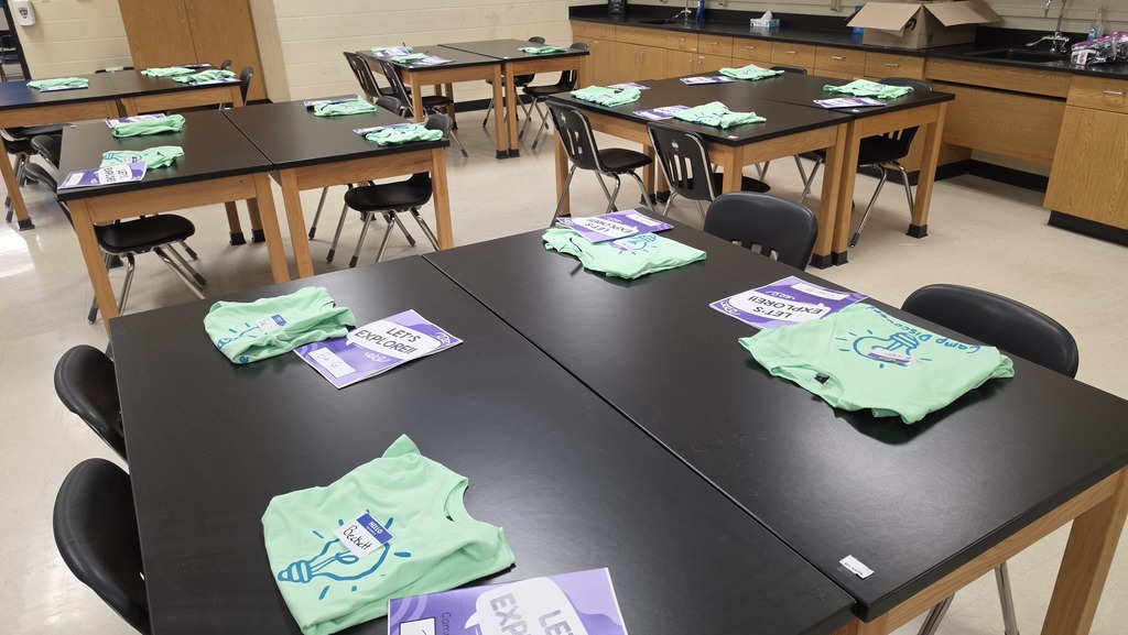 student tables with Camp Discovery packets and t-shirts neatly arranged