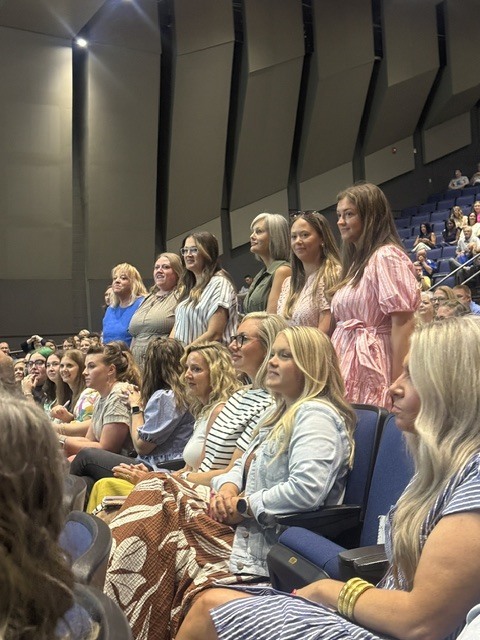 Teachers in the PAC watching a presentation.  Six teachers are standing up to be recognized for thier achievments. 