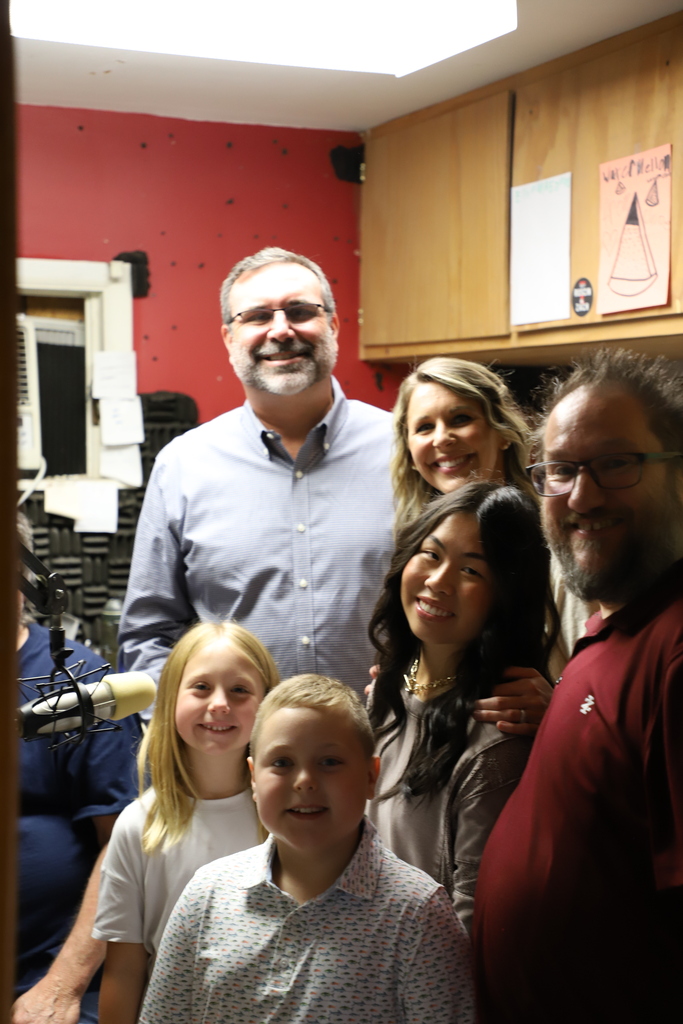 Group photo of Harrison Public Schools students, Principal Mark Ditmanson, and radio studio staff smiling together inside the ESPN radio booth.