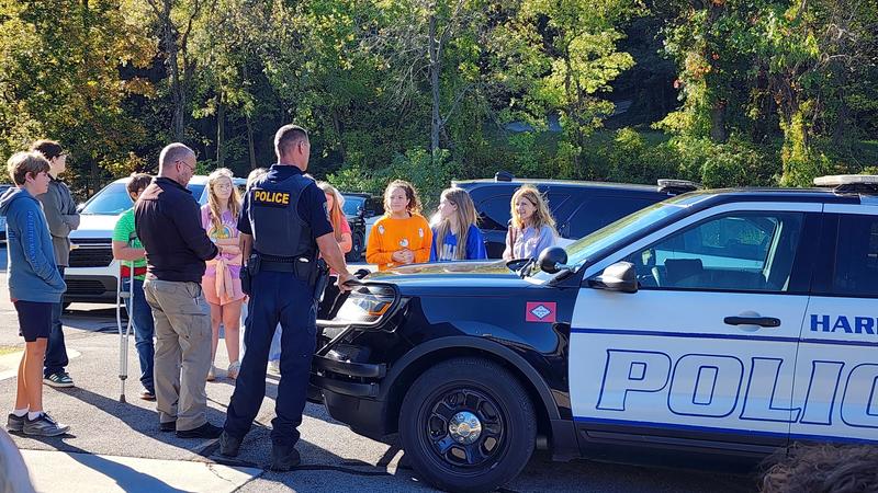 students looking at police car