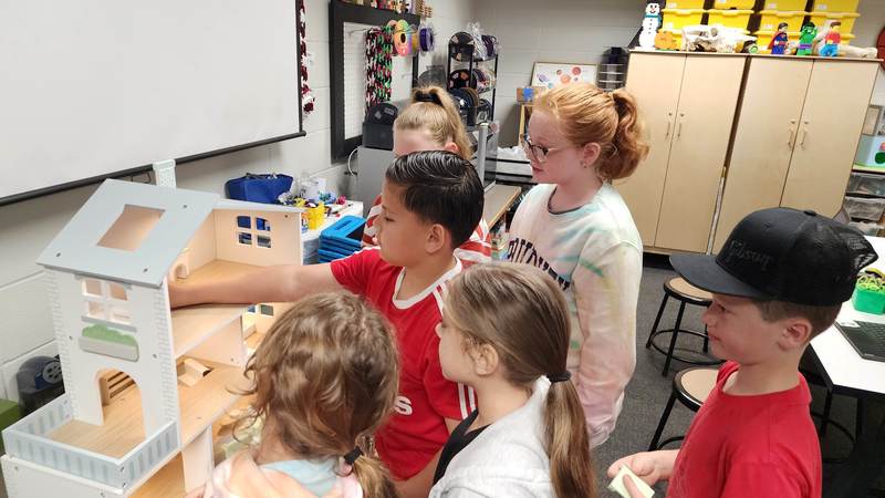 students adding furniture to doll house