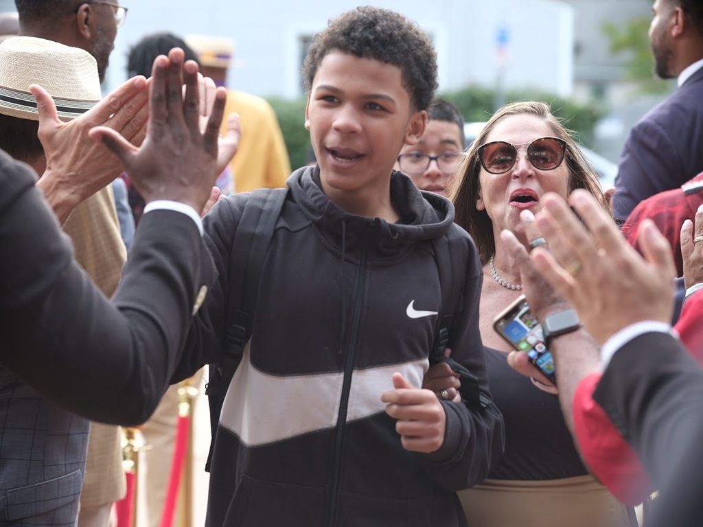 McDonough student high-fives Calling All Brothers members on the first day of school.