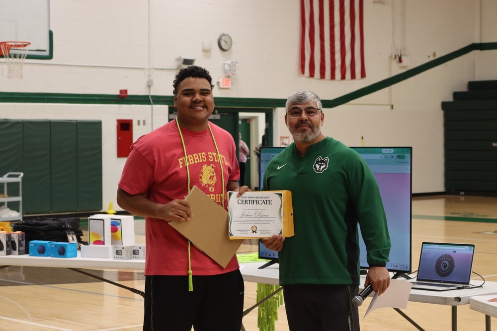 josh dyson holds up his most improved senior award and poses with principal robles