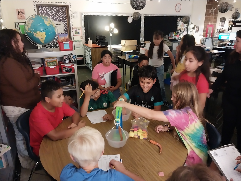 students sit at a circle table and measure the mass of carrots