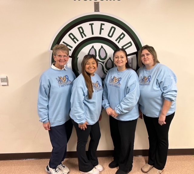 our secretary and medical team poses in front of the hartford husky logo with their diabiates awareness sweaters on