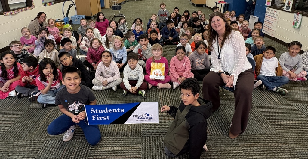 ms billings from the mde poses with 1st grade students that hold a sign that says students first
