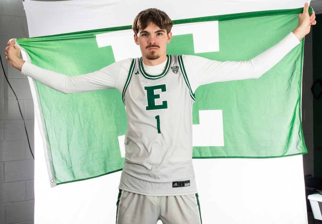 kaden johnson in a white and green eastern michign jersey holding a green eastern flag