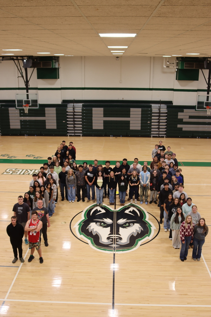 senior class of 2026 in the shape of an H in front of the husky head logo on the gym floor