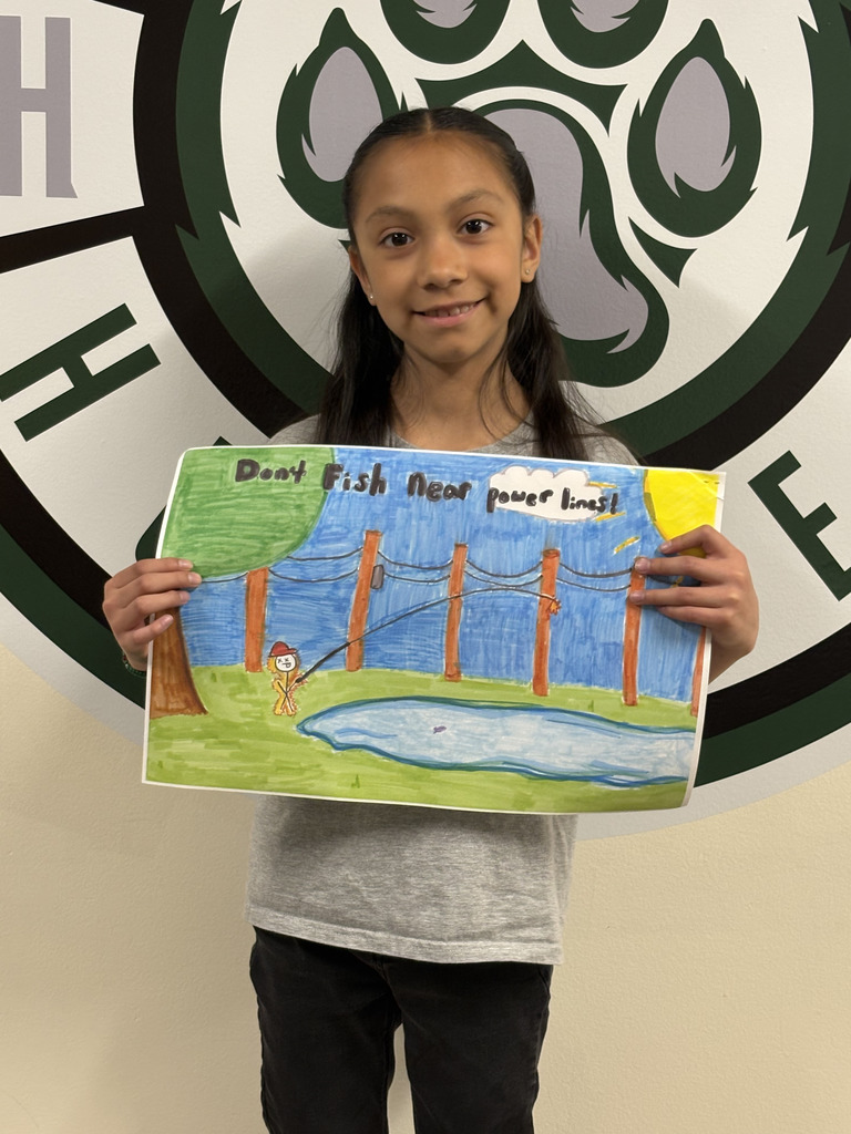 a student holds a poster with a fisherman in the woods that reads dont fish near power lines