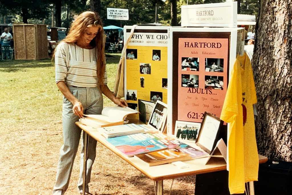 A collection of vintage Hartford Public Schools photographs featured in Hartford Rewind | Volume 2. The images include students posing with academic trophies, science classroom activities, elementary students reading and participating in class, hands-on classroom projects, cultural learning activities, CPR training, group class photos, Adult Education displays at a community event, students gathered outdoors, and various classroom and school life scenes from past decades. The photographs capture everyday moments, learning experiences, and student life throughout Hartford Public Schools' history.