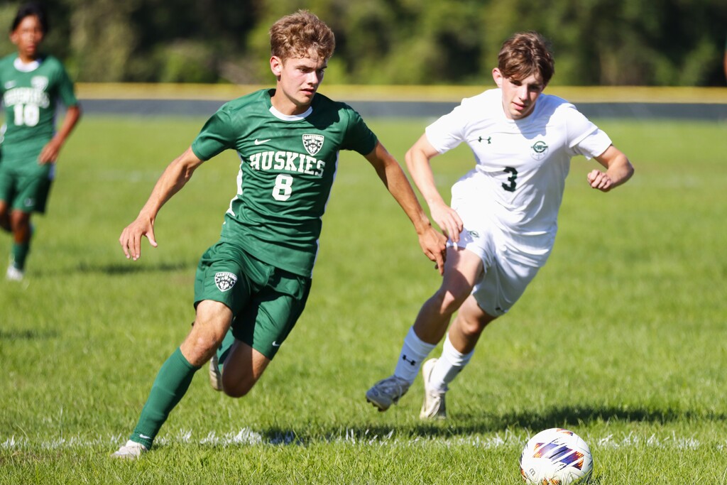 a hartford soccer player pushes the ball ahead against the rival team. looking to score