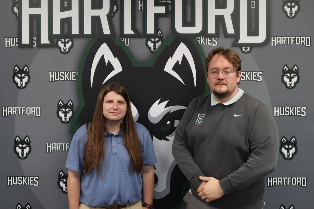 hps tech team brody and forrest post in front of the hartford huskies backdrop