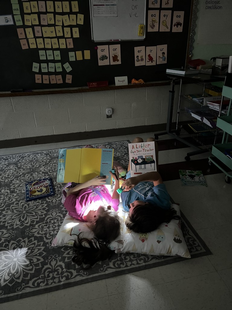 kids reading book with flashlight on floor