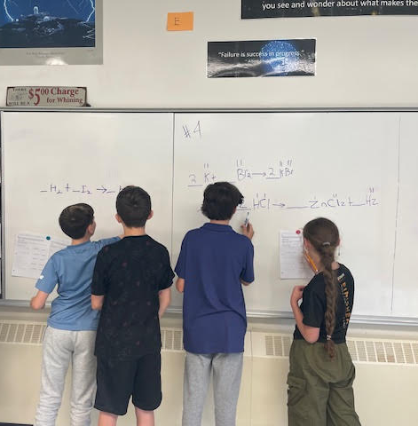 Students writing on whiteboard.