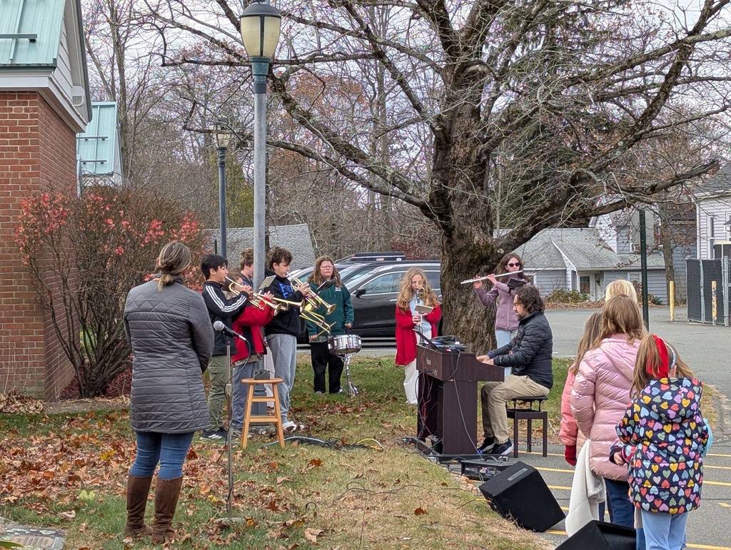 Band playing with teacher at piano outside
