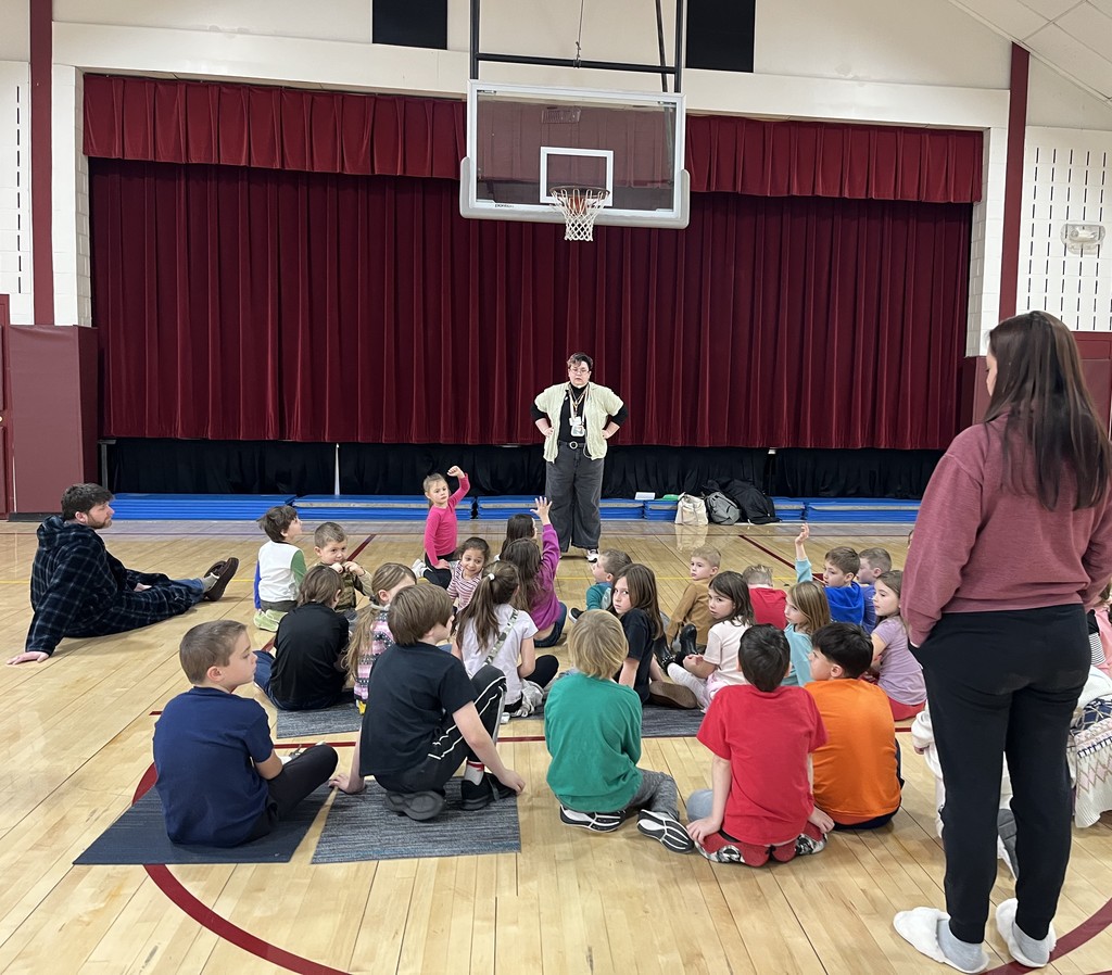 students on floor of gym watching adult