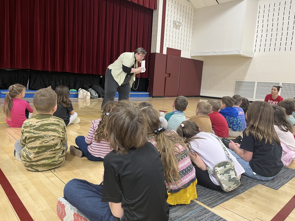 students on floor in a gym watching a grown up.
