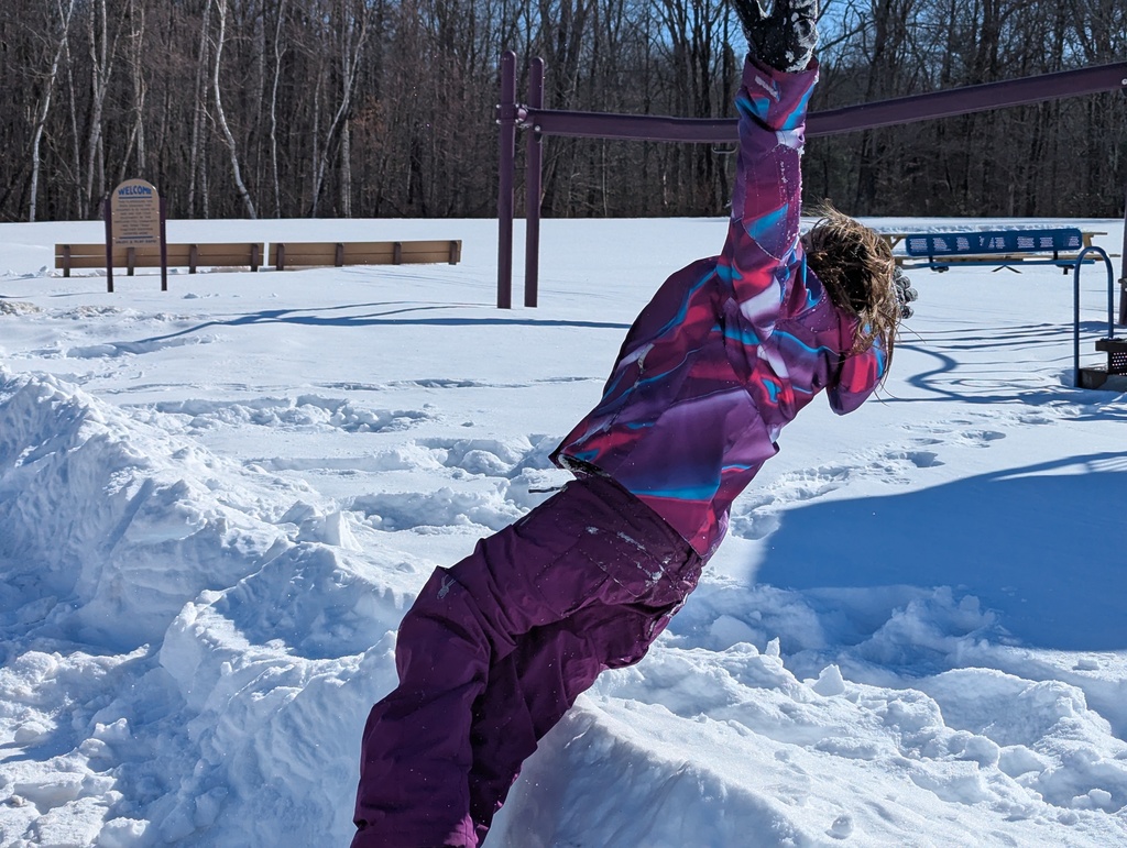 child in snow gear jumping