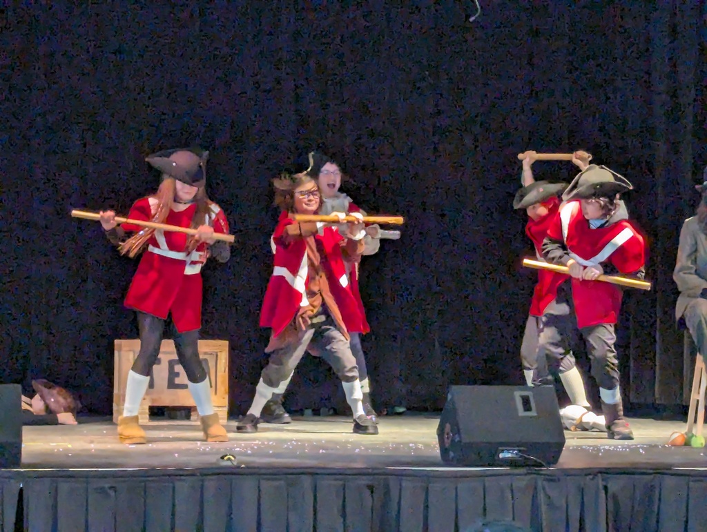 Students in red costumes on stage