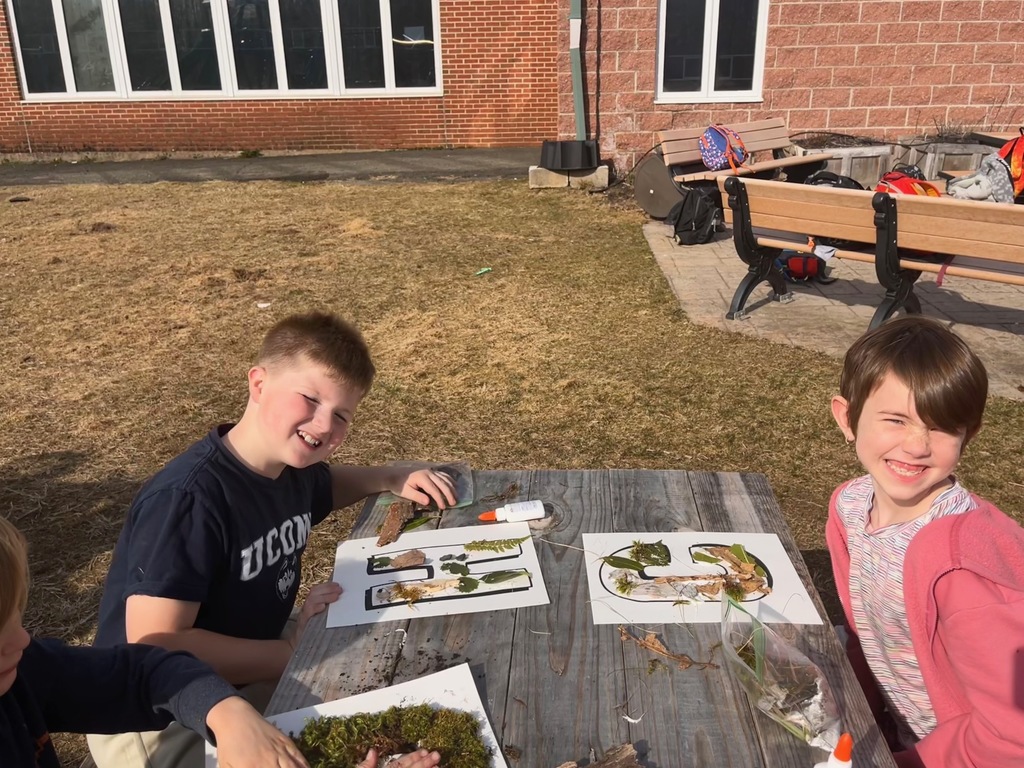 Boy and girl at picnic table with craft outside