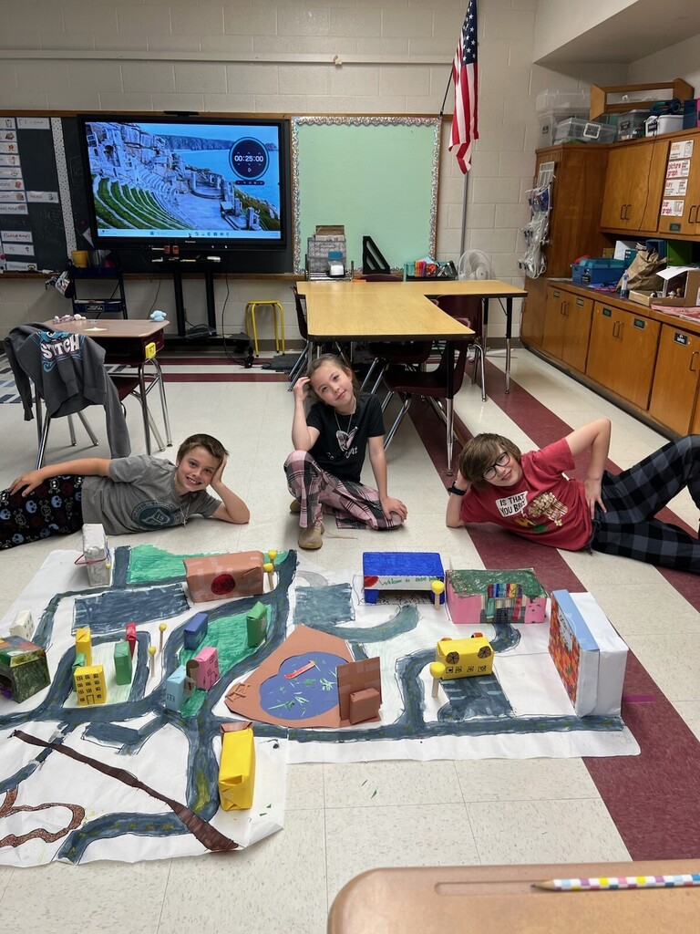 Kids on floor with a paper created town.