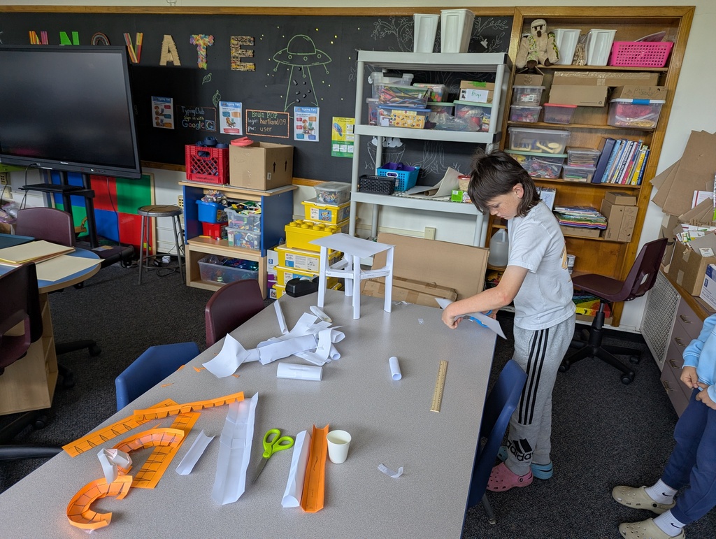 Boy  working on paper roller coaster at table.