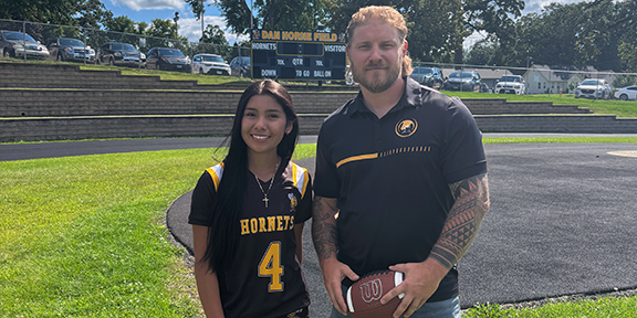 Coach and player stand on the football field.