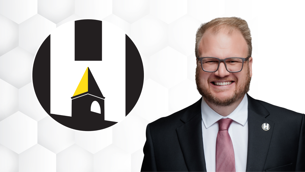 Goetz smiling near Harvard CUSD 50 logo