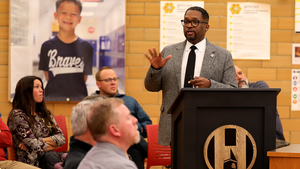 Dr. White presenting his 18-month plan and people listening in the audience.
