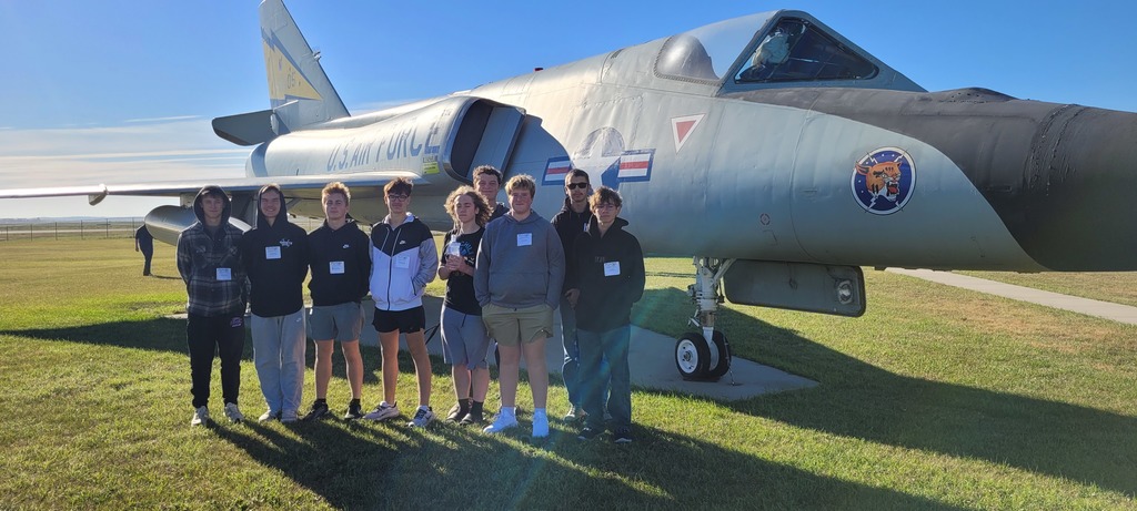 Students pose by a fighter jet