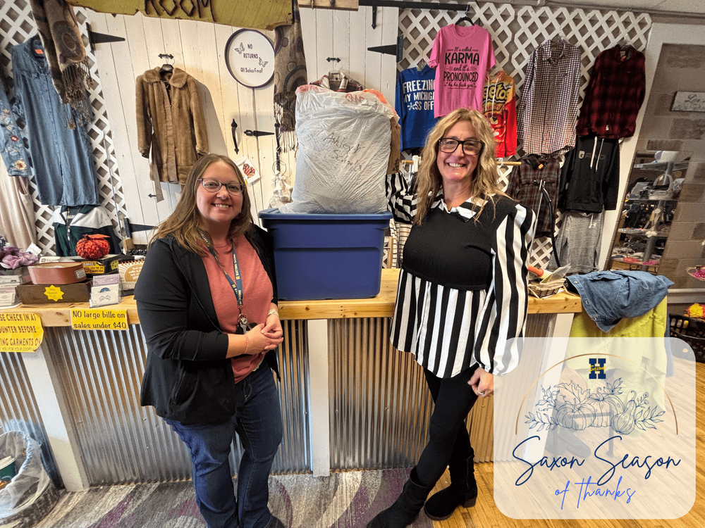 Ashley VanBelkum standing next to Chris Warner in front of a cash register near a bundle of clothes that are being donated.