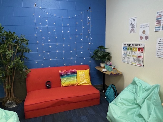 a room with a couch, bean bags and some string lights handing on the wall