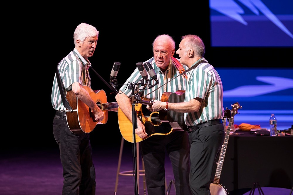Members of the Kington Trio leaning into a microphone during their performance at the Hastings Performing Arts Center